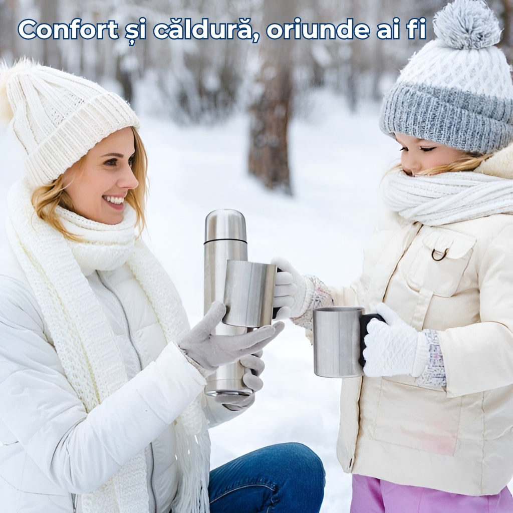 O mamica cu copil se afla in padure inzapezita. Copilul tine canile din inox in maini iar mamica ei tine termosul din inox Koken. Termosul ofera confort si caldura oriunde ai fi.