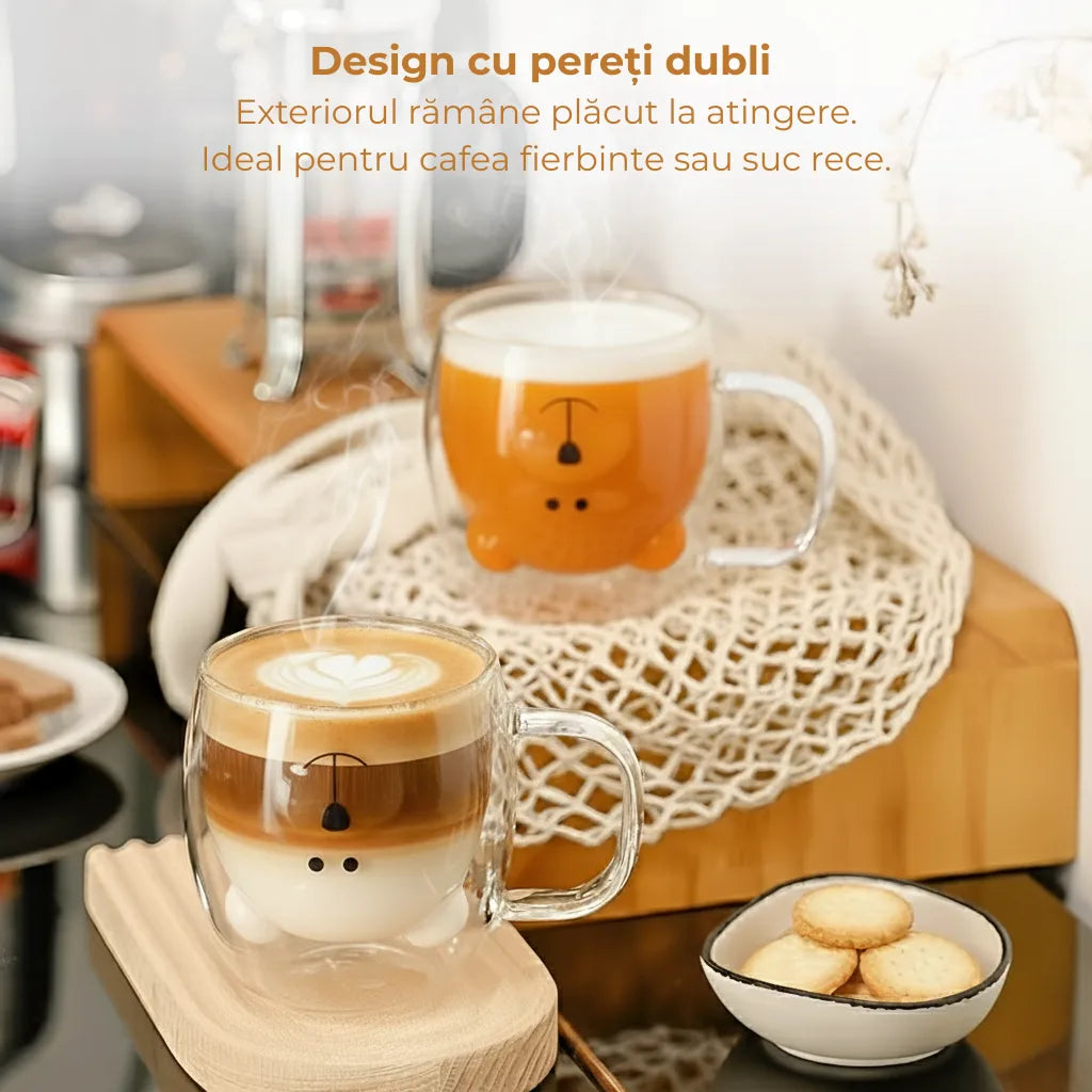 Doua cani cu pereti dubli stau pe suporturi de lemn. O cana este cu latte fierbinte iar alta cana cu suc de morcovi. Alaturi de ele sta o farfurioara cu biscuiti. Pe poza este prezent textul "Design cu pereti dubli - Exterorul ramane placut la atingere. Ideal pentru cafea fierbinte sau suc rece.